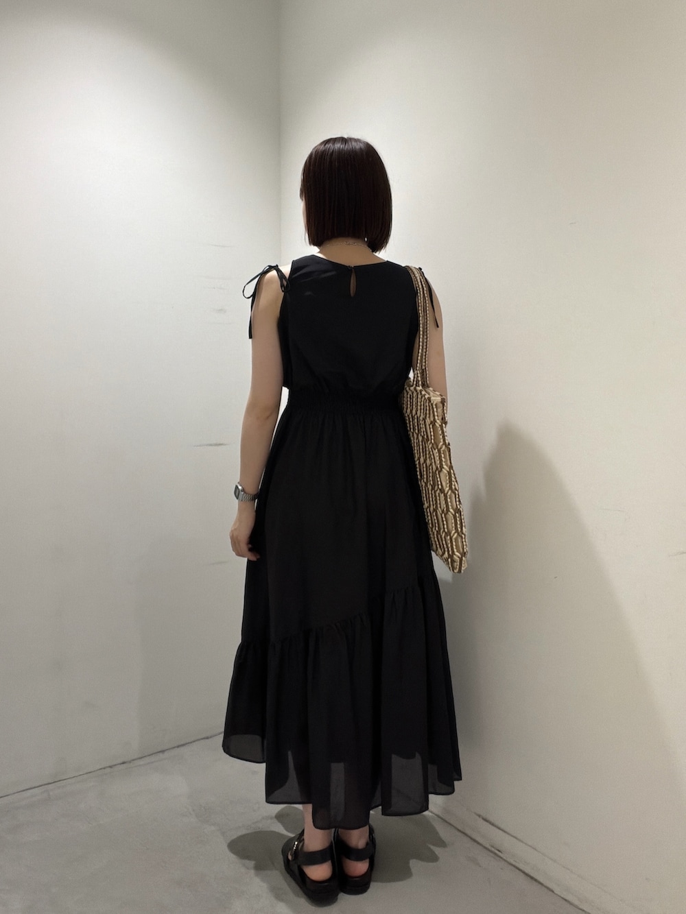 ブラック系のワンピース、ブラウン系のトートバッグ、ブラック系のサンダルを着用したレディースの夏コーディネートの3枚目の写真