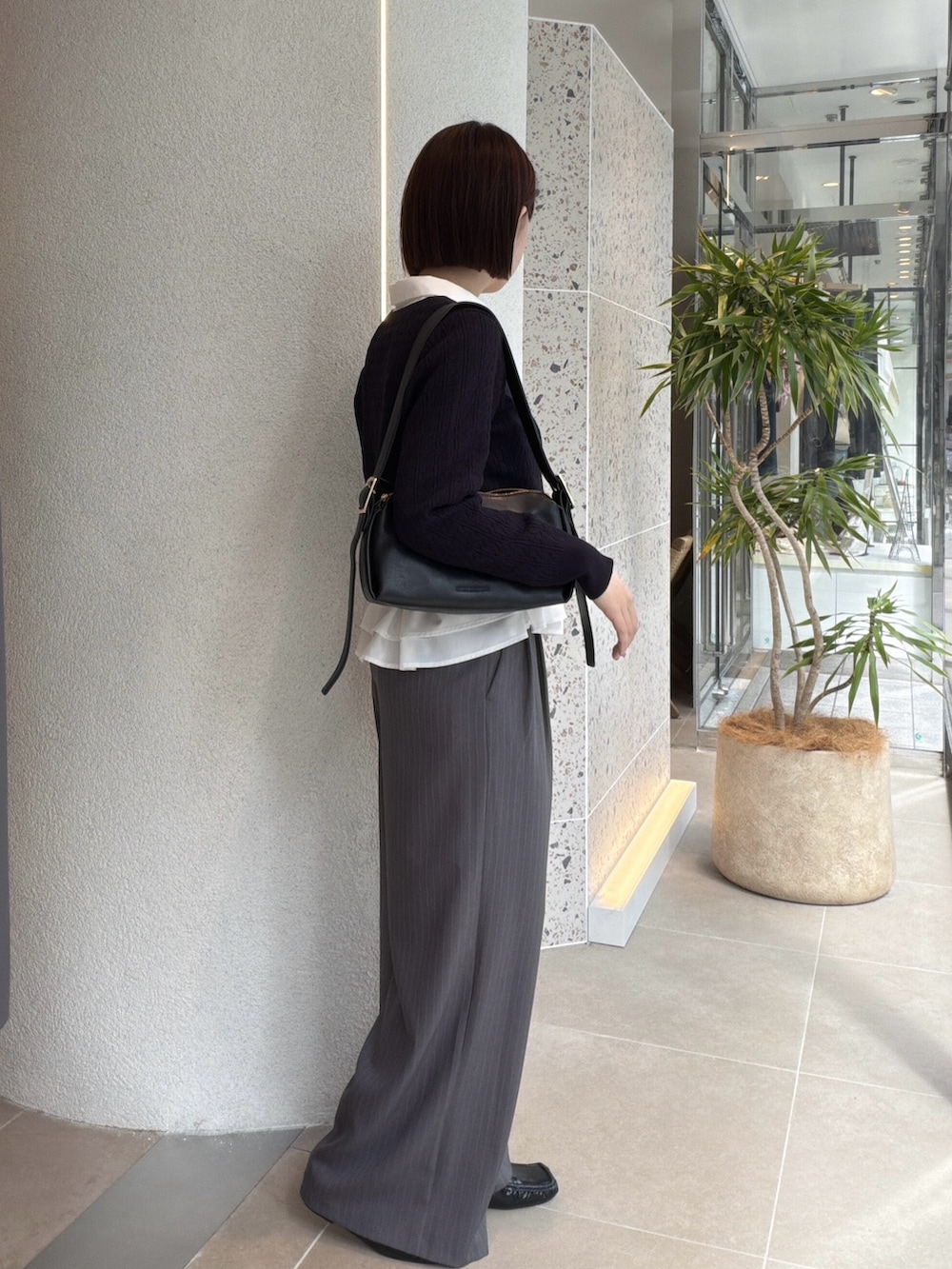 ホワイト系のシャツ/ブラウス、ブルー系のニット/セーター、ブラック系のショルダーバッグを着用したレディースの秋コーディネートの2枚目の写真