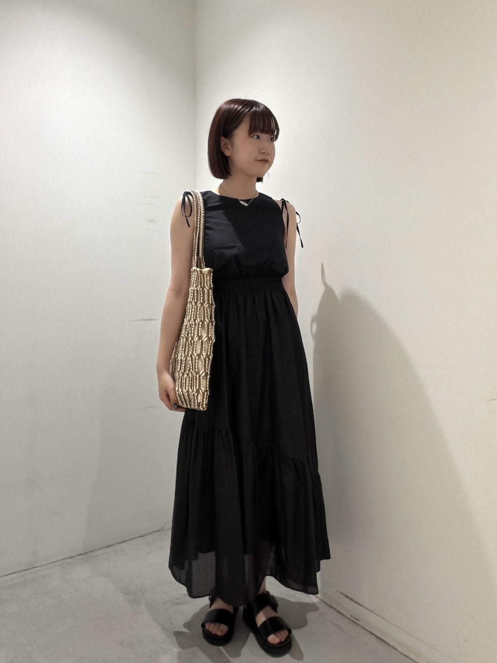 ブラック系のワンピース、ブラウン系のトートバッグ、ブラック系のサンダルを着用したレディースの夏コーディネートの6枚目の写真