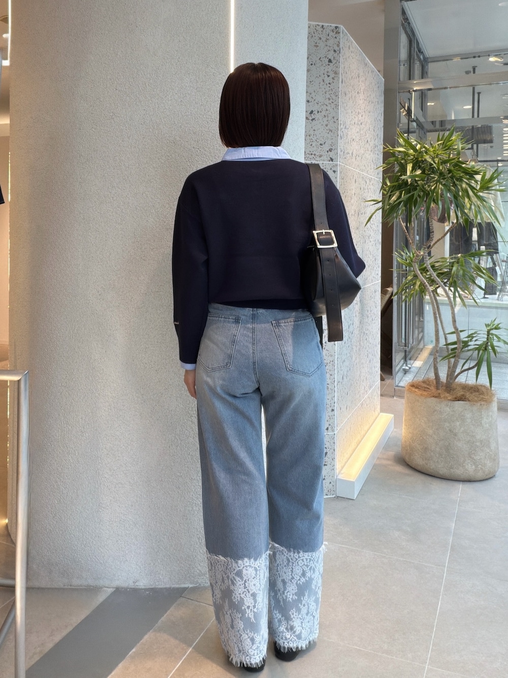 ブルー系のニット/セーター、ブラック系のショルダーバッグ、ブルー系のデニムパンツを着用したレディースの秋コーディネートの3枚目の写真