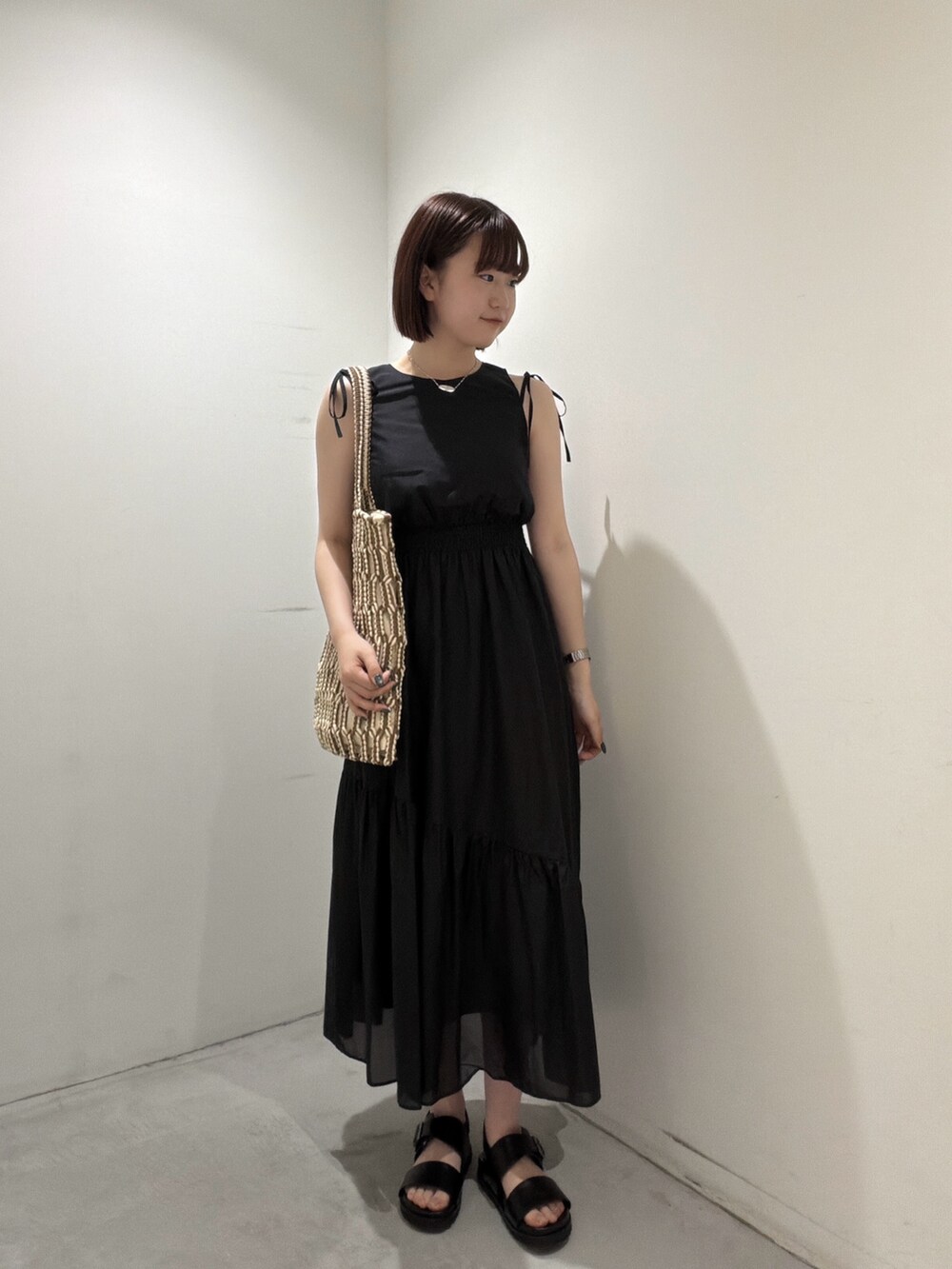 ブラック系のワンピース、ブラウン系のトートバッグ、ブラック系のサンダルを着用したレディースの夏コーディネートの5枚目の写真