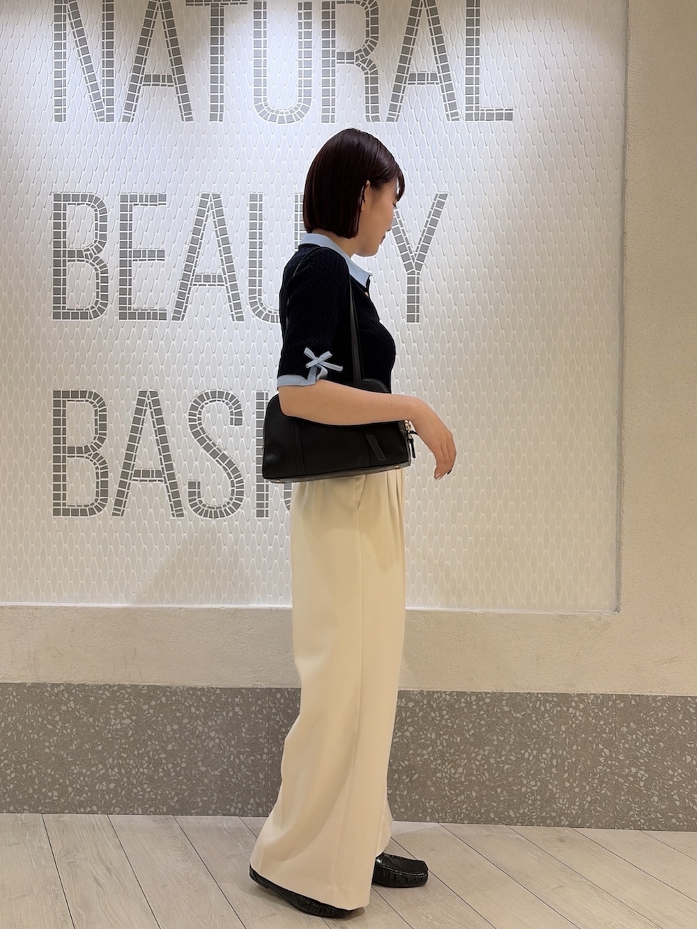 グレー系のニット/セーター、ブラック系のボストンバッグ、ホワイト系のその他パンツを着用したレディースの夏コーディネートの2枚目の写真