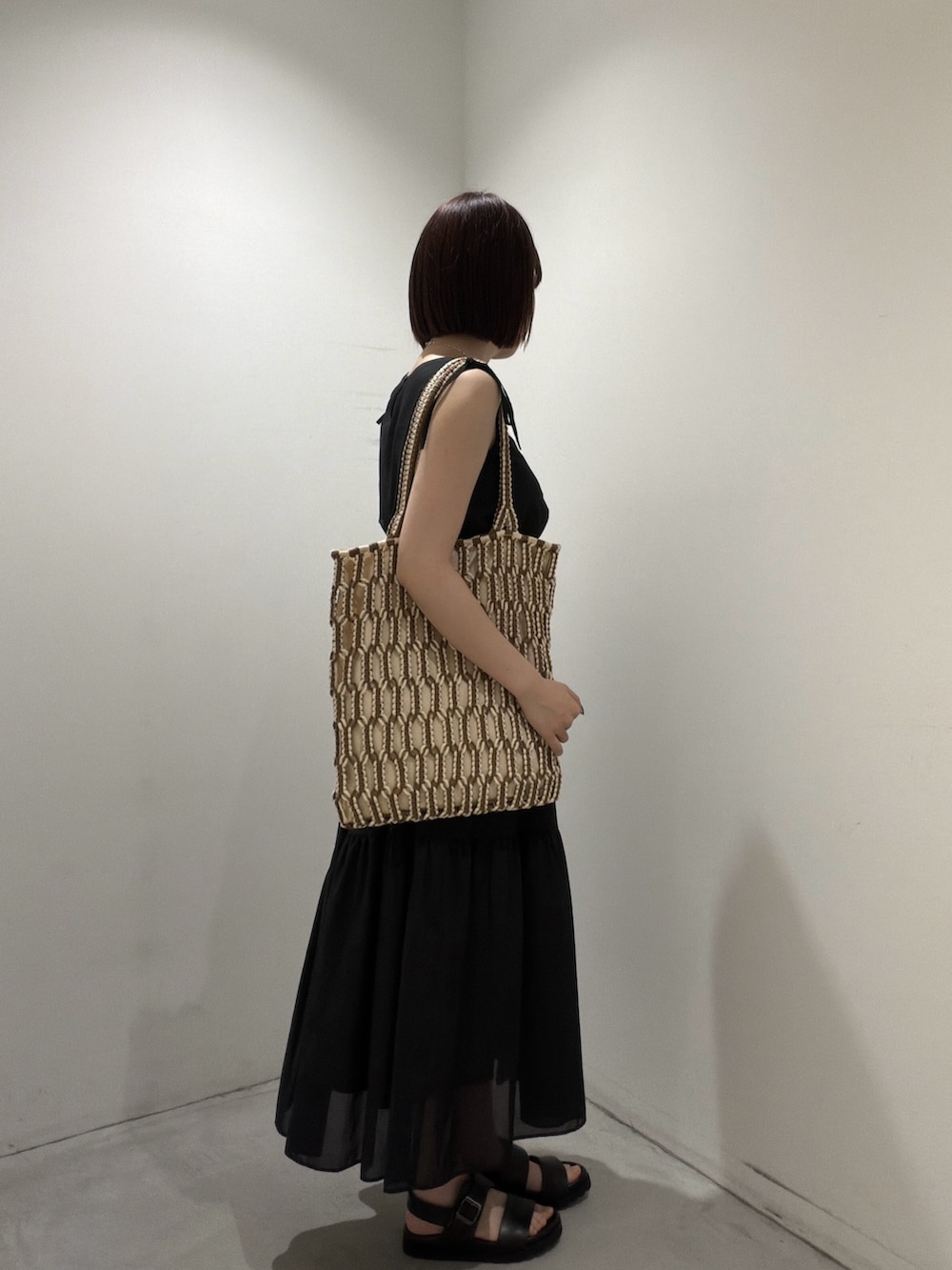 ブラック系のワンピース、ブラウン系のトートバッグ、ブラック系のサンダルを着用したレディースの夏コーディネートの2枚目の写真