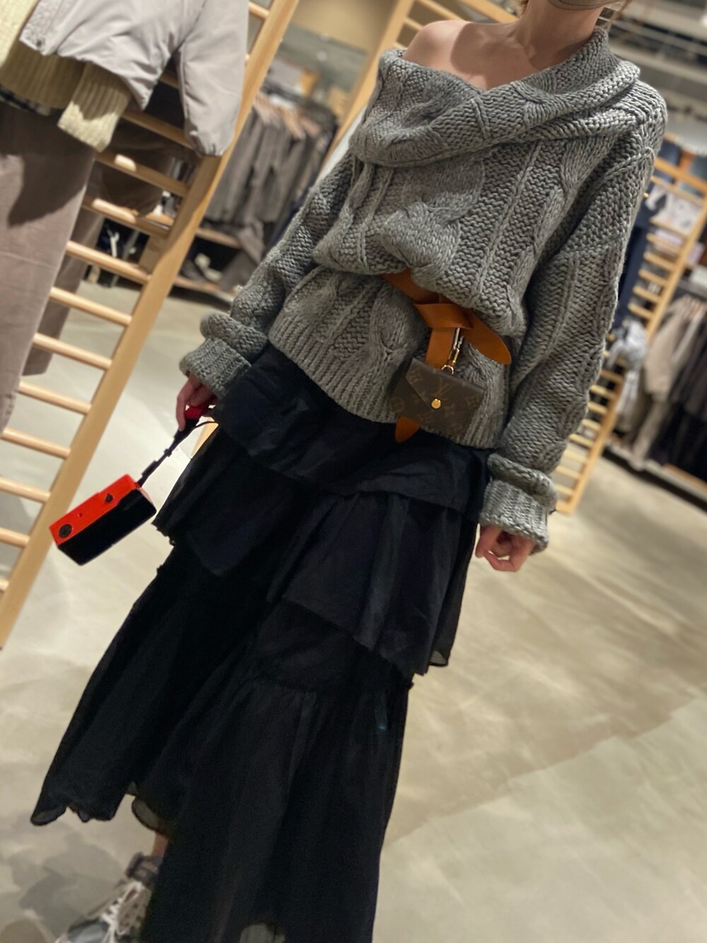 ブラック系のスカート、グレー系のニット/セーター、グレー系のスニーカーを着用したレディースの冬コーディネートの2枚目の写真