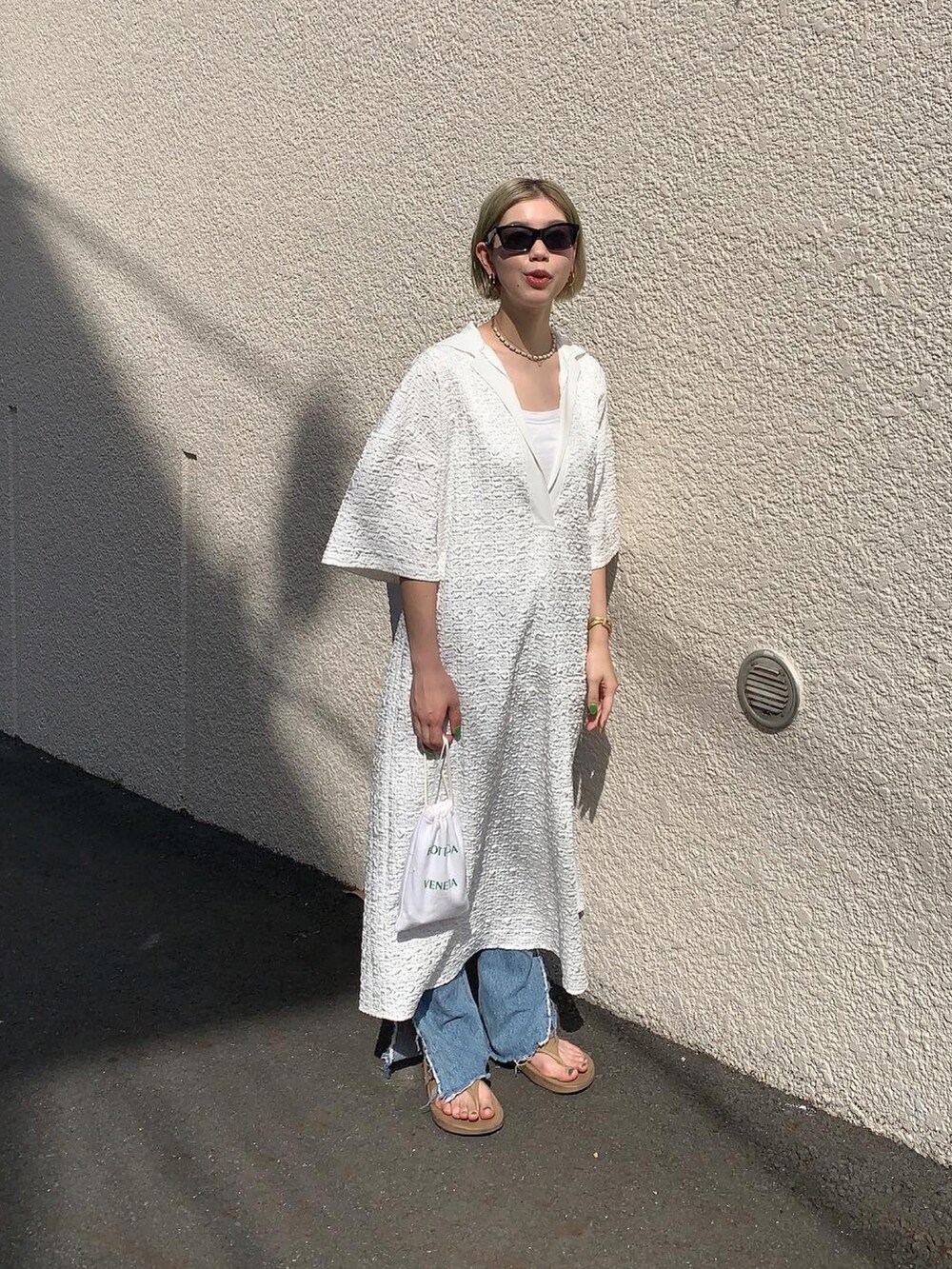 ホワイト系のワンピース、ブルー系のデニムパンツ、ベージュ系のサンダルを着用したレディースの夏コーディネートの2枚目の写真