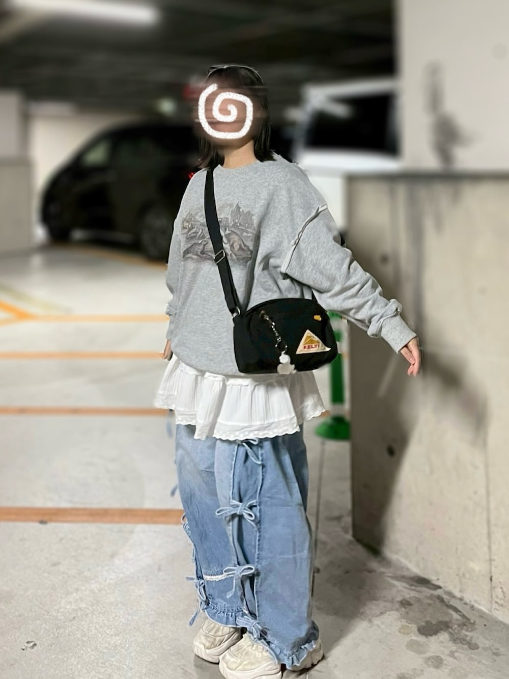 グレー系のスウェット、ブルー系のデニムパンツ、ホワイト系のスカートを着用したレディースの春コーディネートの2枚目の写真