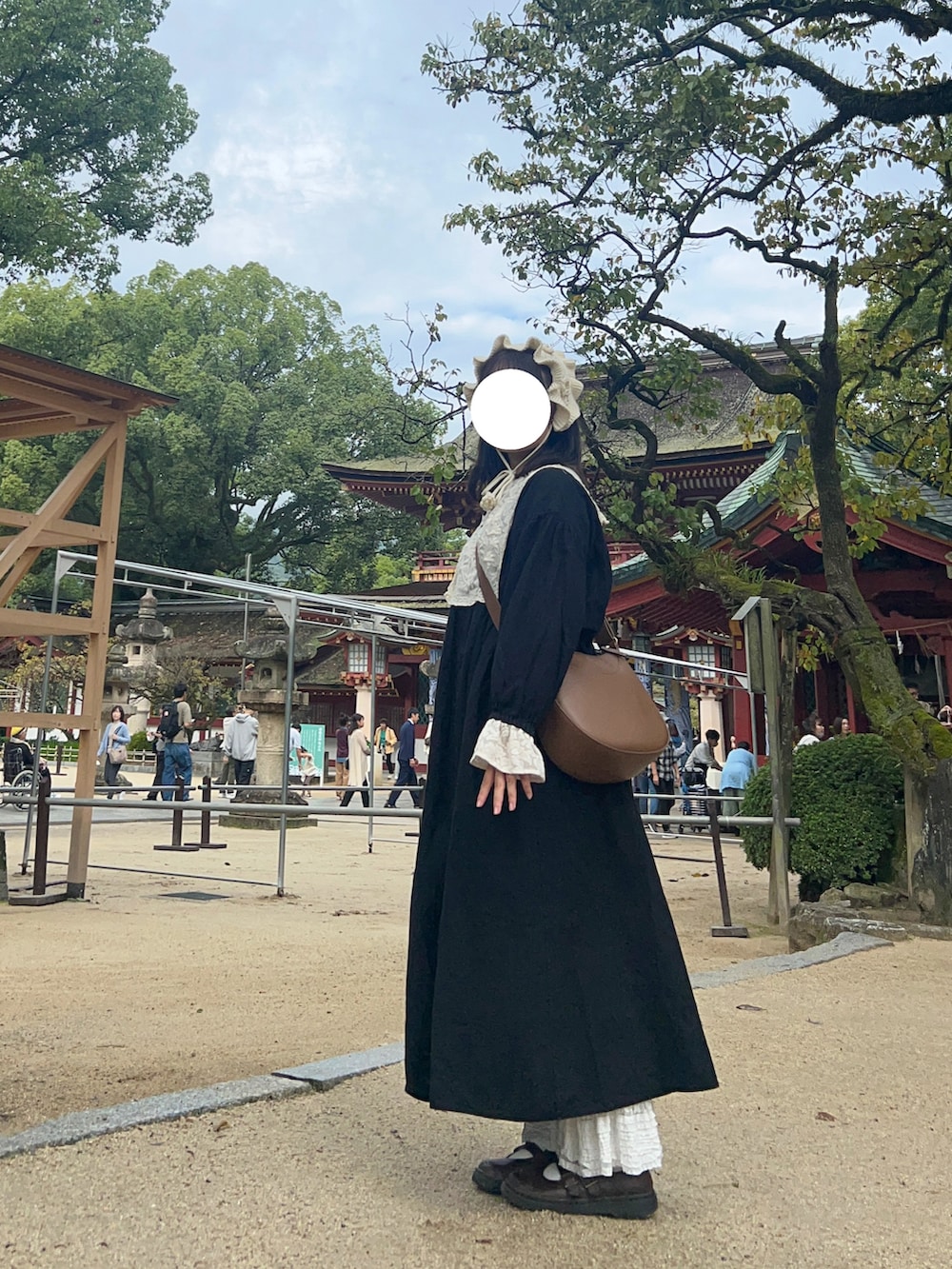 ブラック系のワンピース、ブラウン系のショルダーバッグ、ホワイト系のスラックスを着用したレディースの秋コーディネートの2枚目の写真