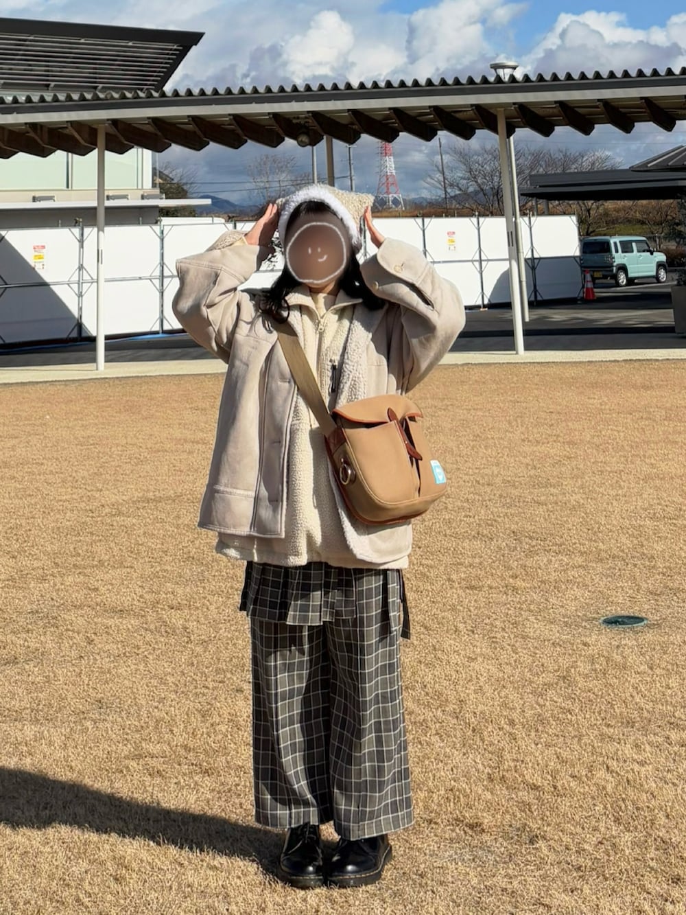 グリーン系のショルダーバッグ、ホワイト系のベスト、ホワイト系のニット/セーターを着用したレディースの冬コーディネートの2枚目の写真