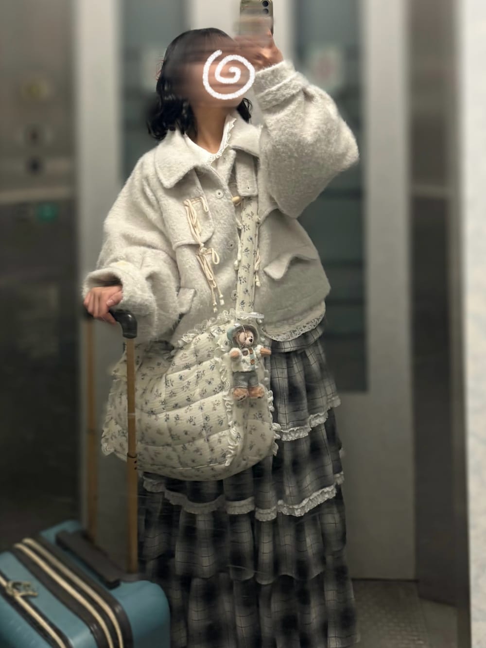 ブラック系のスカート、ブルー系のショルダーバッグ、ホワイト系のカーディガン/ボレロを着用したレディースの冬コーディネートの2枚目の写真