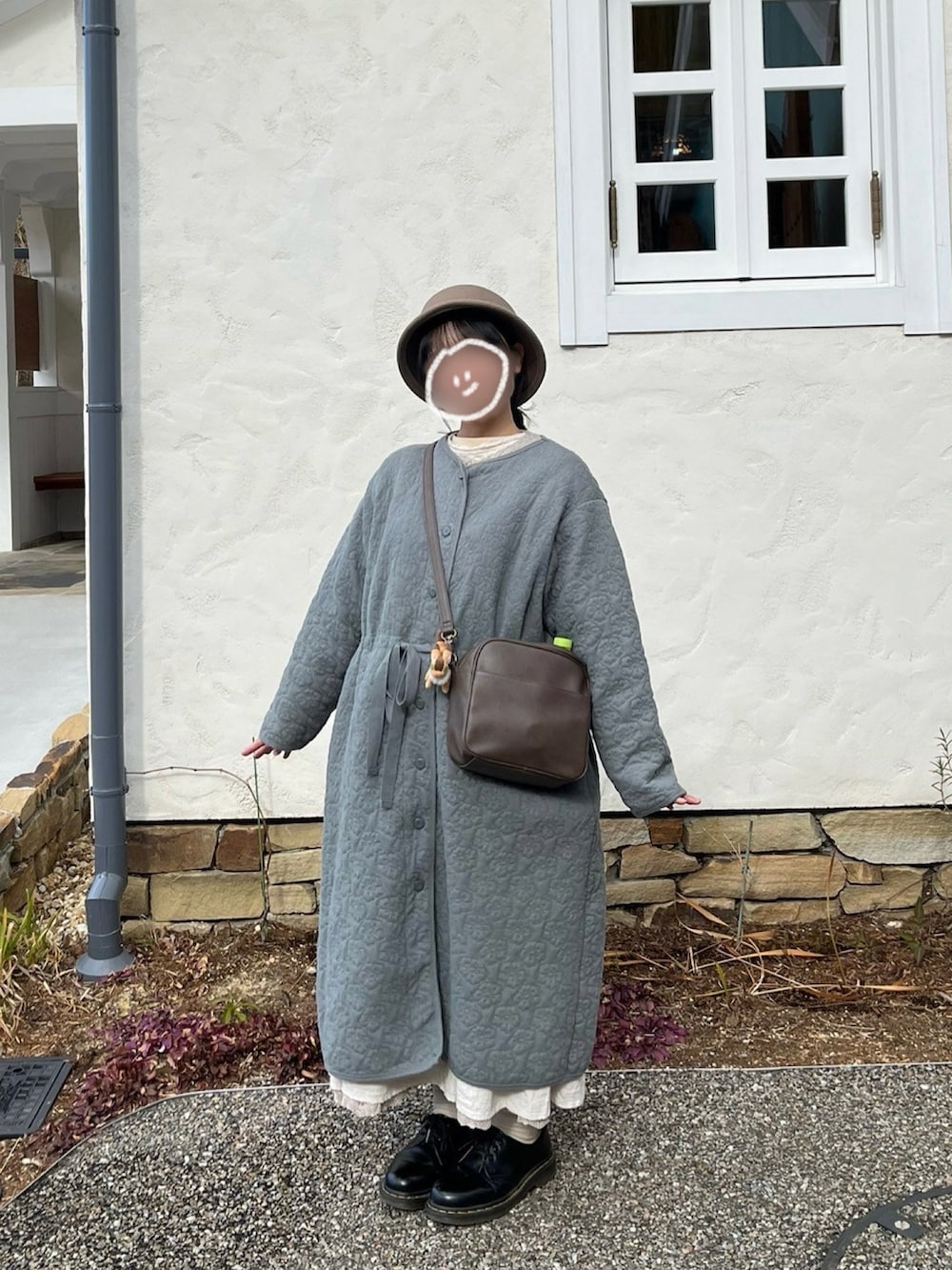 ブラウン系のショルダーバッグ、グレー系のその他アウター、ホワイト系のニット/セーターを着用したレディースの冬コーディネートの2枚目の写真