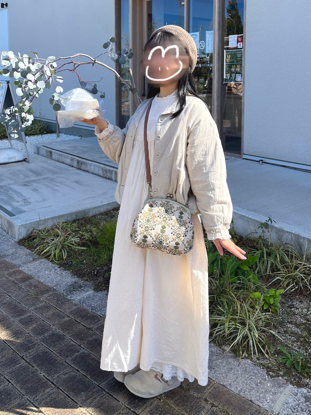 ベージュ系のジャケット/アウター、ホワイト系のワンピース、ベージュ系のハンドバッグを着用したレディースの秋コーディネートの2枚目の写真