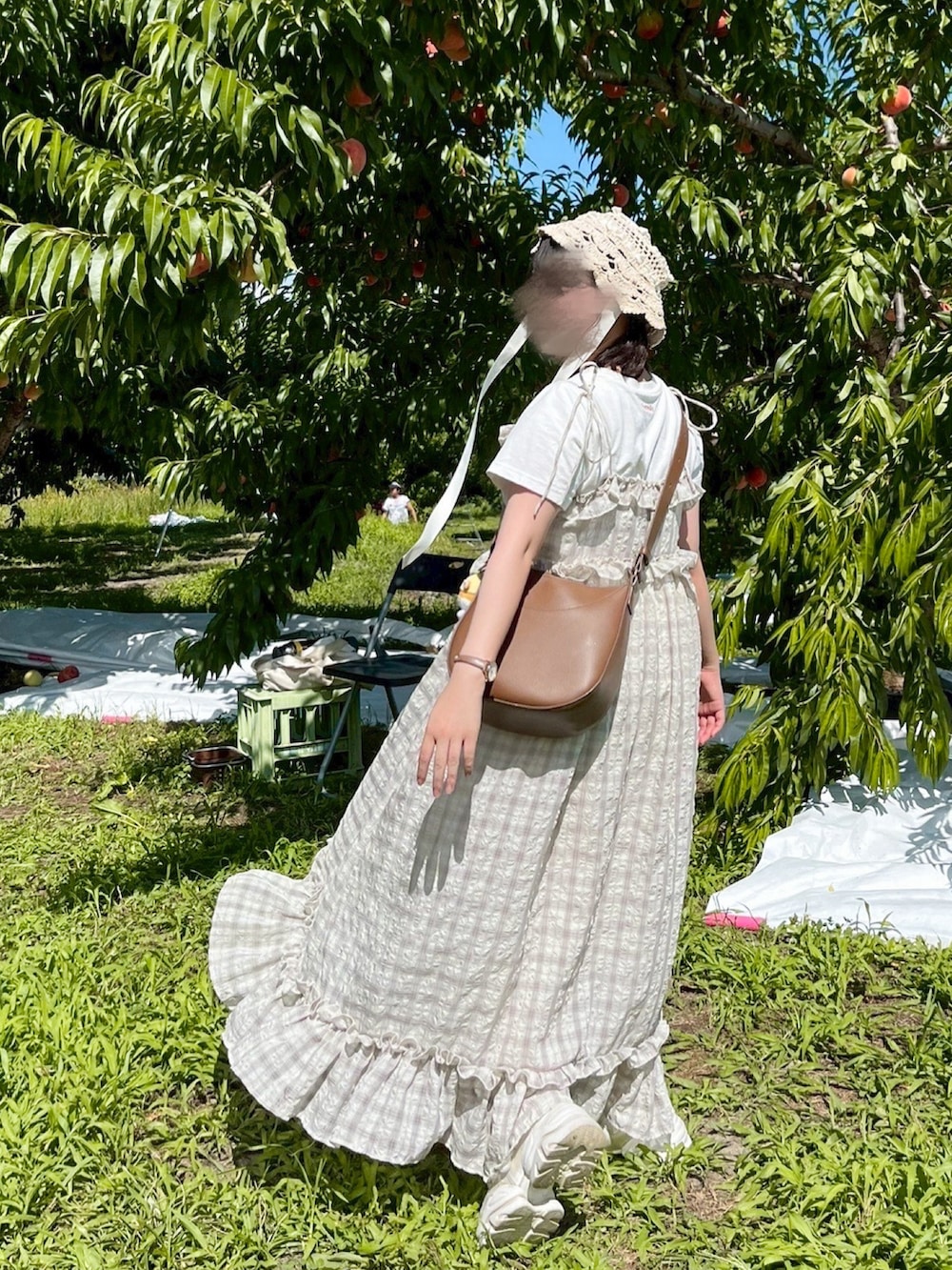 ベージュ系のワンピース、ホワイト系のTシャツ/カットソー、ブラウン系のショルダーバッグを着用したレディースの夏コーディネートの2枚目の写真