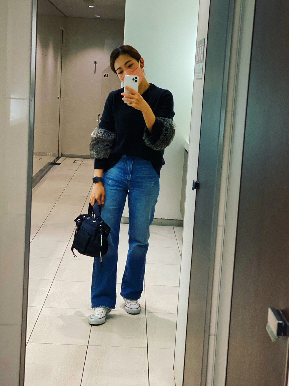 ブラック系のニット/セーター、ブルー系のデニムパンツ、ブラック系のショルダーバッグを着用したレディースの冬コーディネートの2枚目の写真