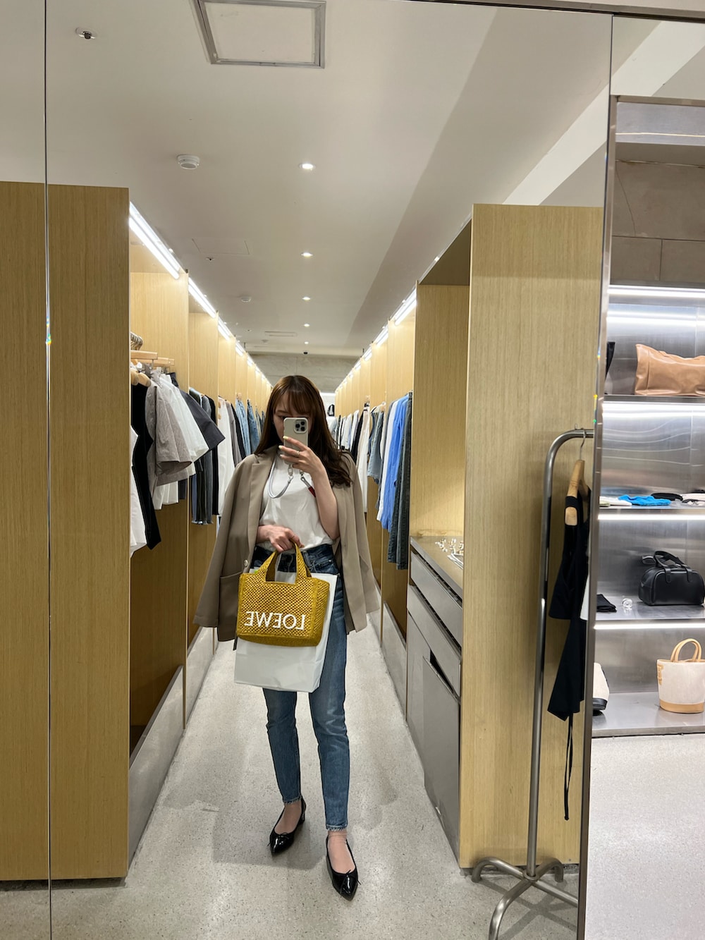 ベージュ系のテーラードジャケット、ブルー系のデニムパンツ、イエロー系のバッグを着用したレディースの春コーディネートの2枚目の写真