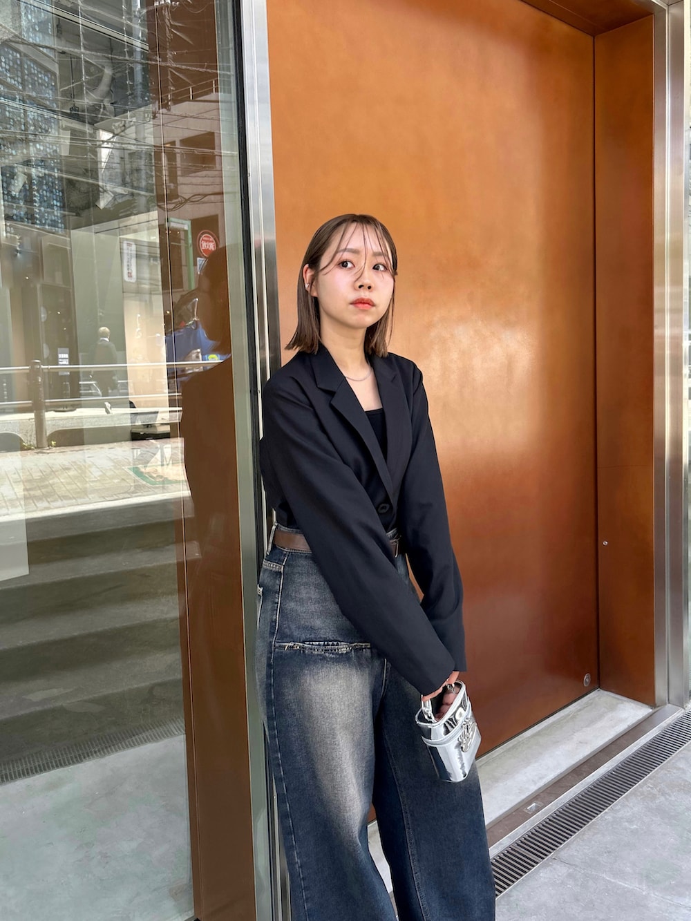 ブラック系のテーラードジャケット、ブラック系のキャミソール、シルバー系のハンドバッグを着用したレディースの春コーディネートの4枚目の写真