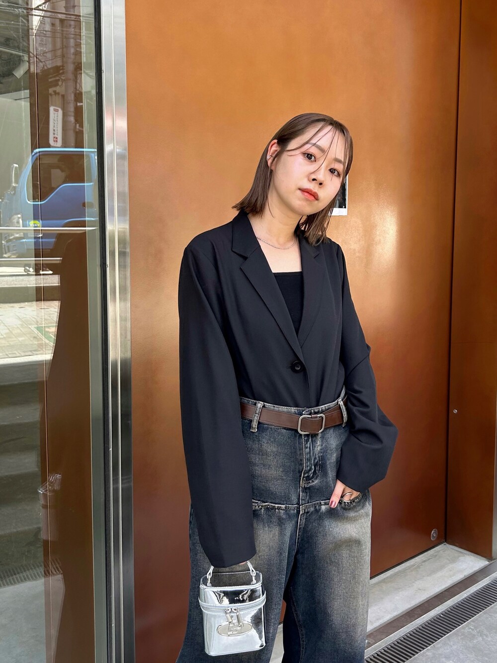 ブラック系のテーラードジャケット、ブラック系のキャミソール、シルバー系のハンドバッグを着用したレディースの春コーディネートの2枚目の写真