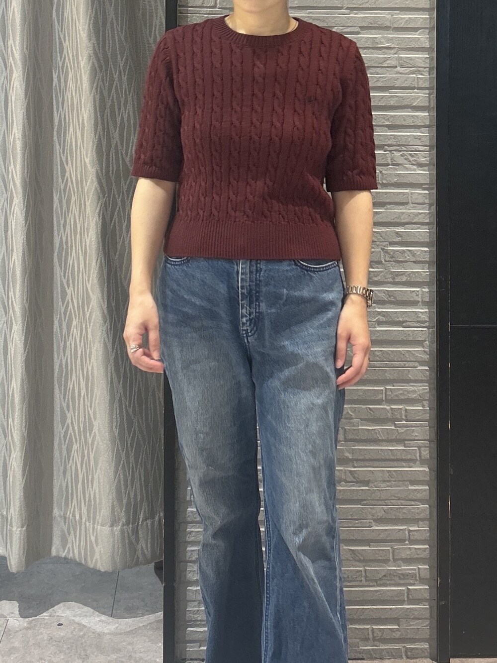 レッド系のニット/セーター、ブルー系のデニムパンツ、ブラック系のパンプスを着用したレディースの秋コーディネートの6枚目の写真