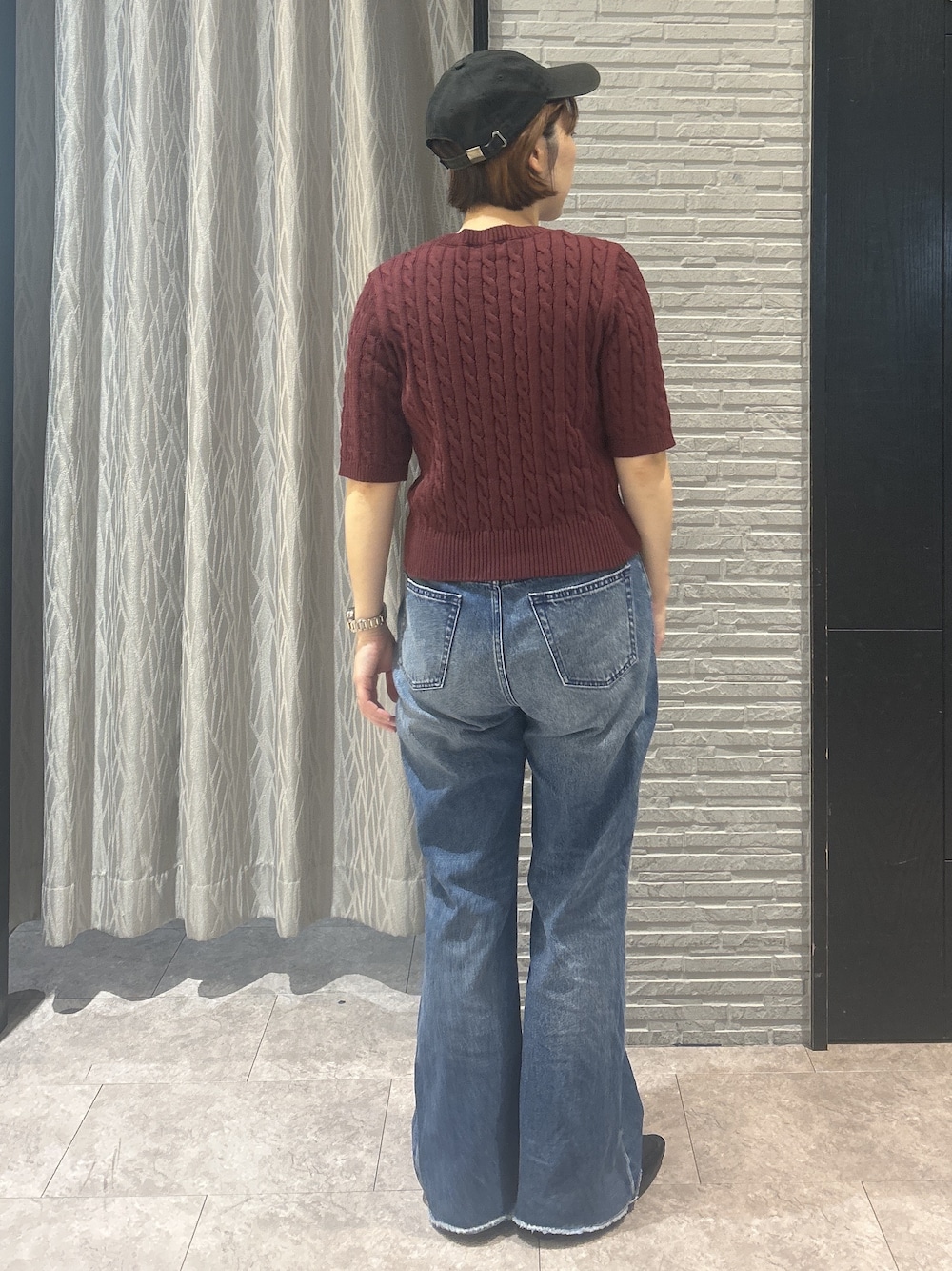 レッド系のニット/セーター、ブルー系のデニムパンツ、ブラック系のパンプスを着用したレディースの秋コーディネートの4枚目の写真