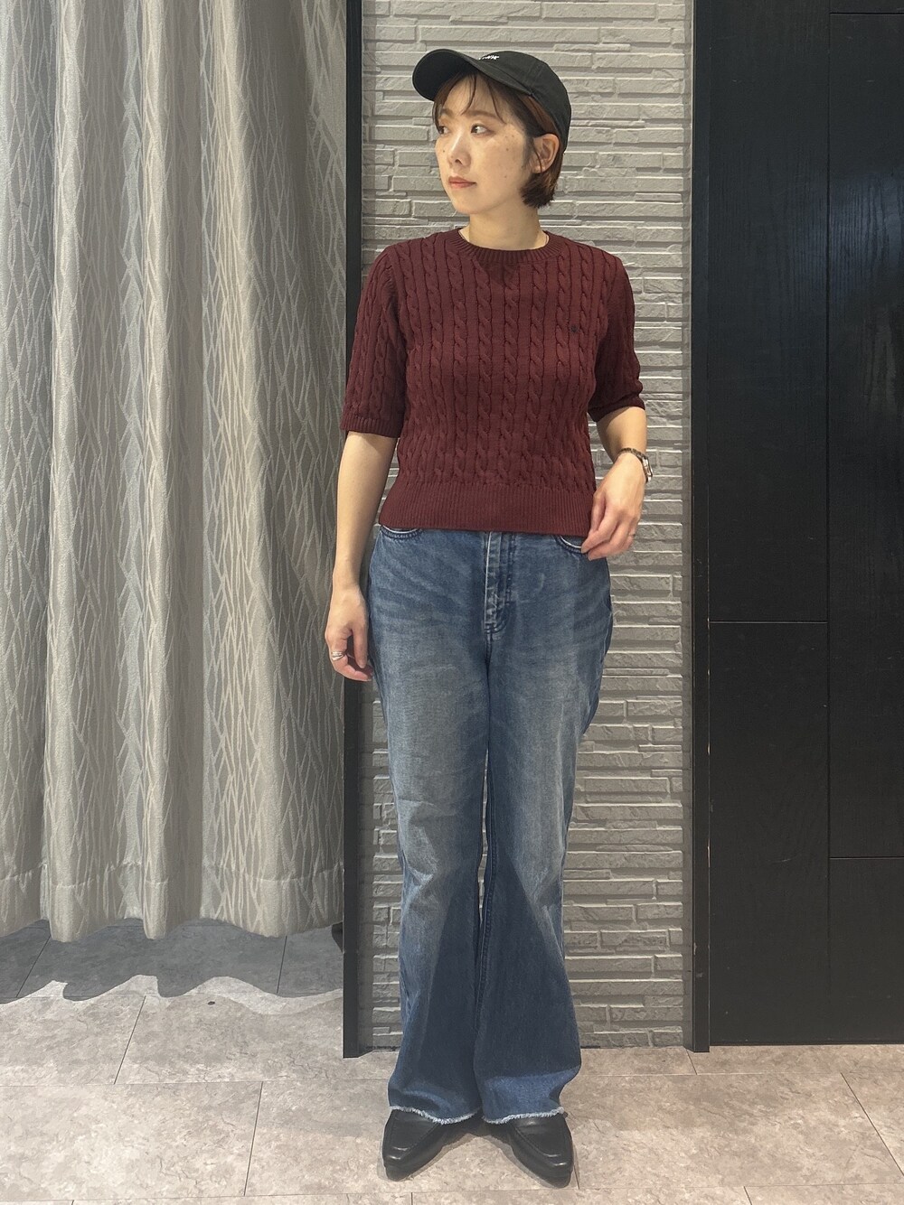 レッド系のニット/セーター、ブルー系のデニムパンツ、ブラック系のパンプスを着用したレディースの秋コーディネートの5枚目の写真