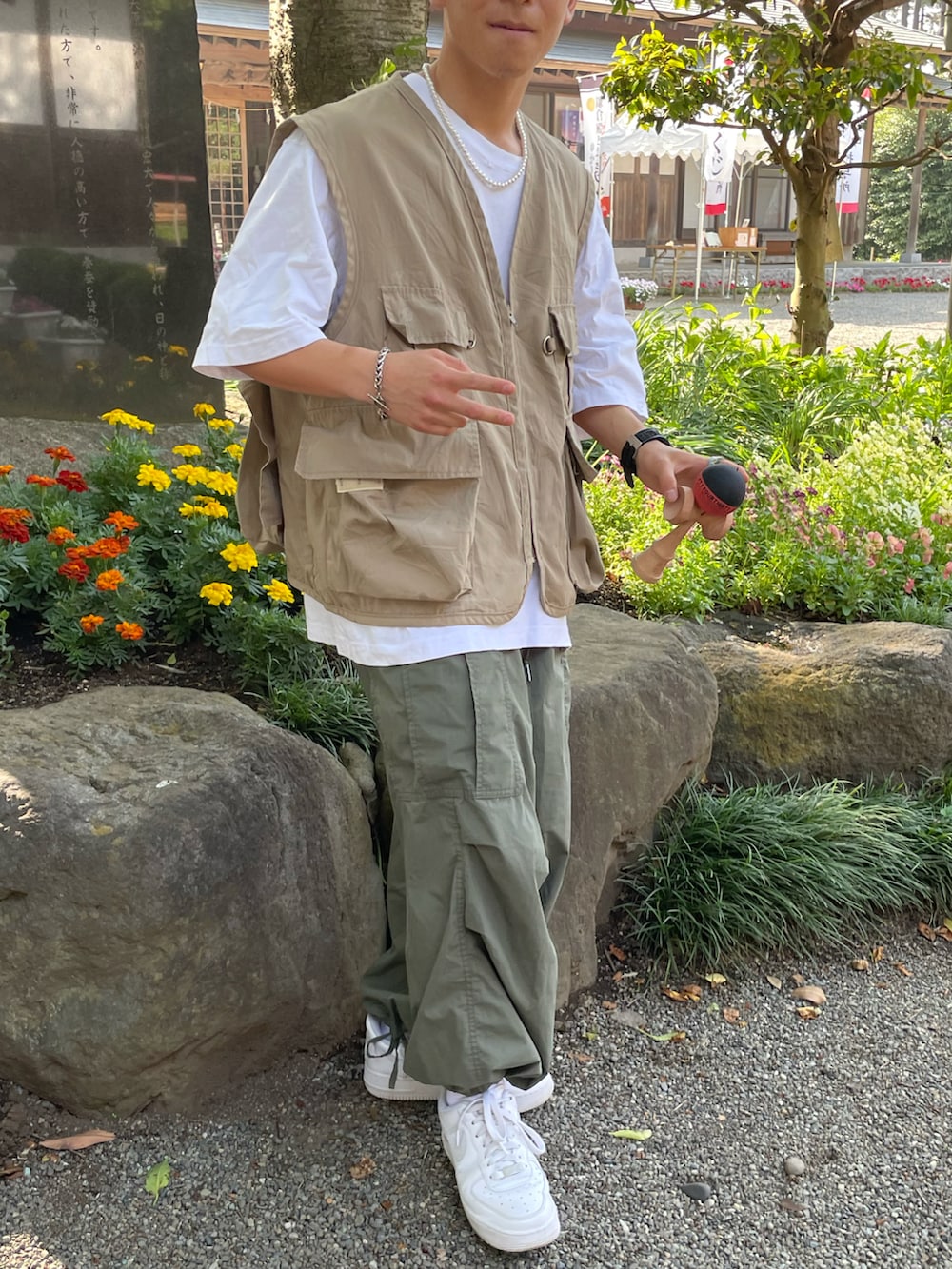 ベージュ系のベスト、ホワイト系のTシャツ/カットソー、グリーン系のカーゴパンツを着用したメンズの春コーディネートの3枚目の写真