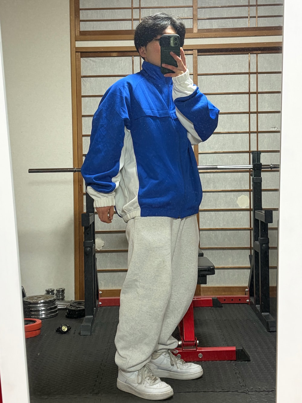 ブルー系のナイロンジャケット、ホワイト系のスウェットパンツ、ホワイト系のスニーカーを着用したメンズの冬コーディネートの2枚目の写真
