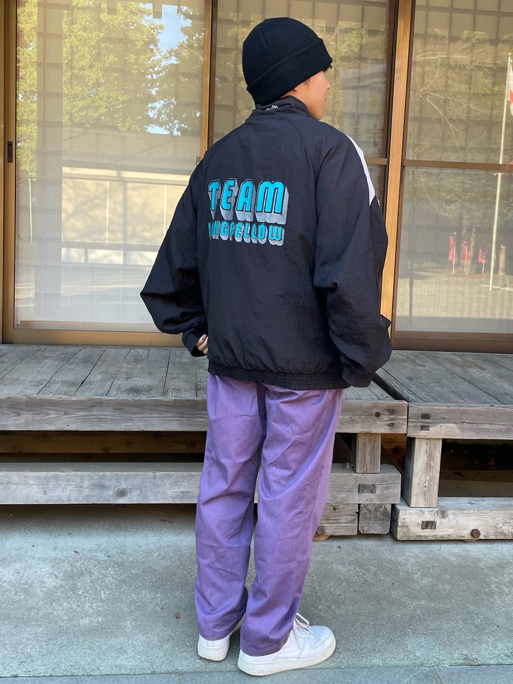 ブラック系のナイロンジャケット、パープル系のチノパンツ、ホワイト系のスニーカーを着用したメンズの秋コーディネートの2枚目の写真