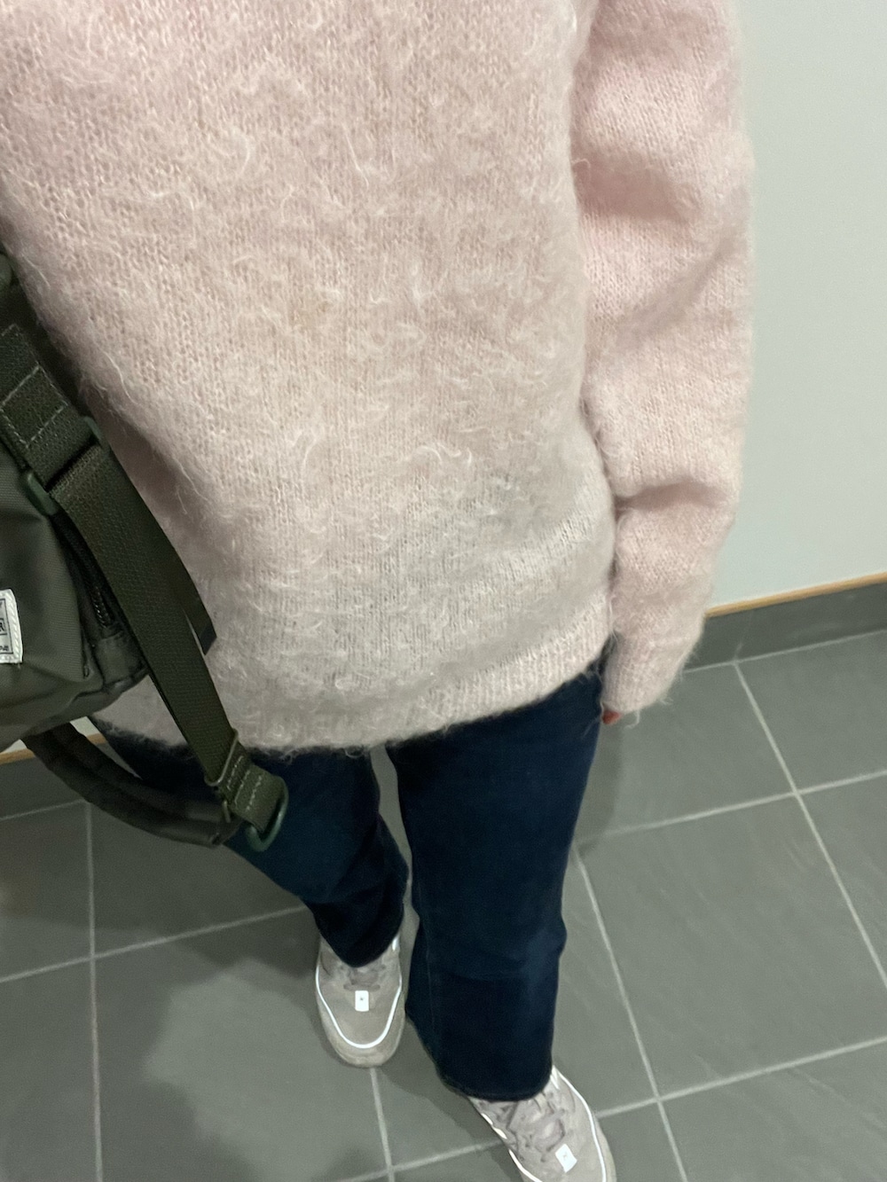 ブルー系のデニムパンツ、グリーン系のショルダーバッグ、ピンク系のニット/セーターを着用したレディースの冬コーディネートの2枚目の写真