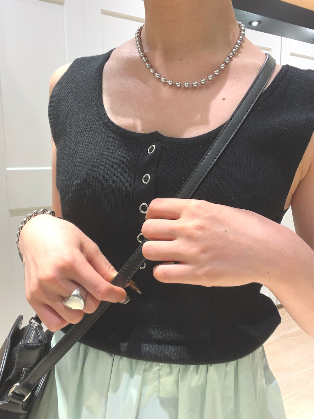 グリーン系のスカート、ブラック系のタンクトップ、ブラック系のショルダーバッグを着用したレディースの夏コーディネートの3枚目の写真