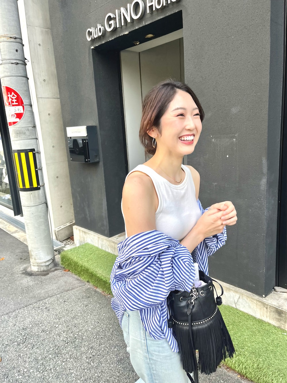 ブラック系のハンドバッグ、ブルー系のシャツ/ブラウス、ホワイト系のタンクトップを着用したレディースの秋コーディネートの2枚目の写真