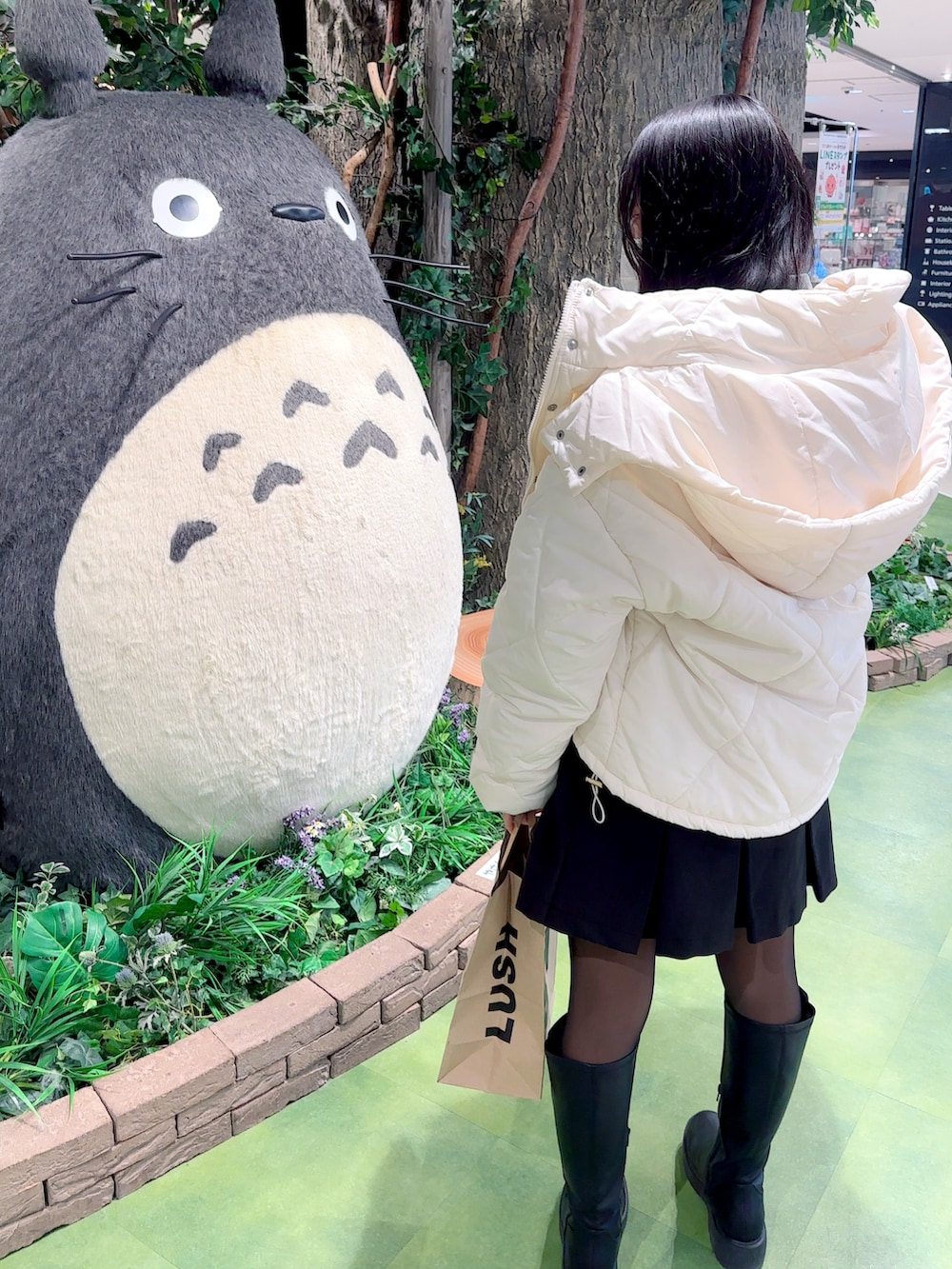 ブラック系のスカート、ホワイト系のダウンジャケット/コートを着用したレディースの春コーディネートの2枚目の写真