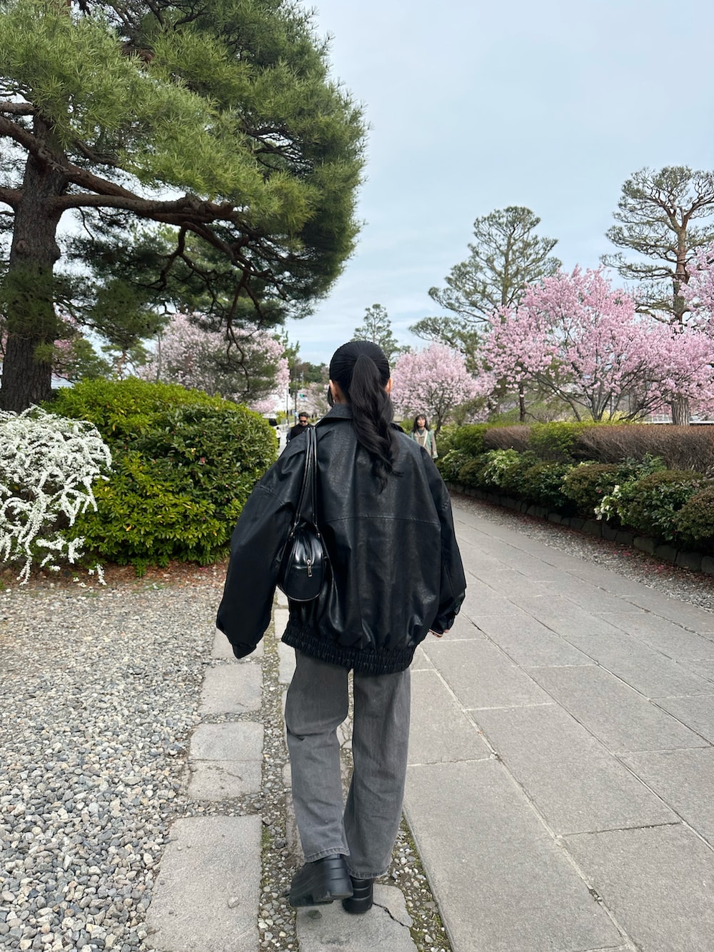 ブラック系のブルゾン、ブルー系のシャツ/ブラウス、グレー系のデニムパンツを着用したレディースの春コーディネートの2枚目の写真