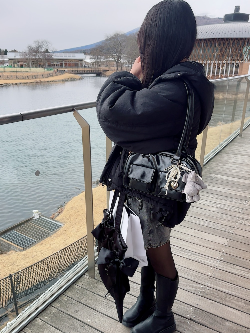 ブラック系のダウンジャケット/コート、ホワイト系のニット/セーター、グレー系のスカートを着用したレディースの冬コーディネートの2枚目の写真