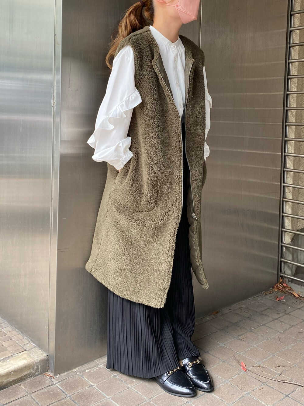 グリーン系のベスト、ホワイト系のシャツ/ブラウス、ブラック系のパンツを着用したレディースの秋コーディネートの3枚目の写真