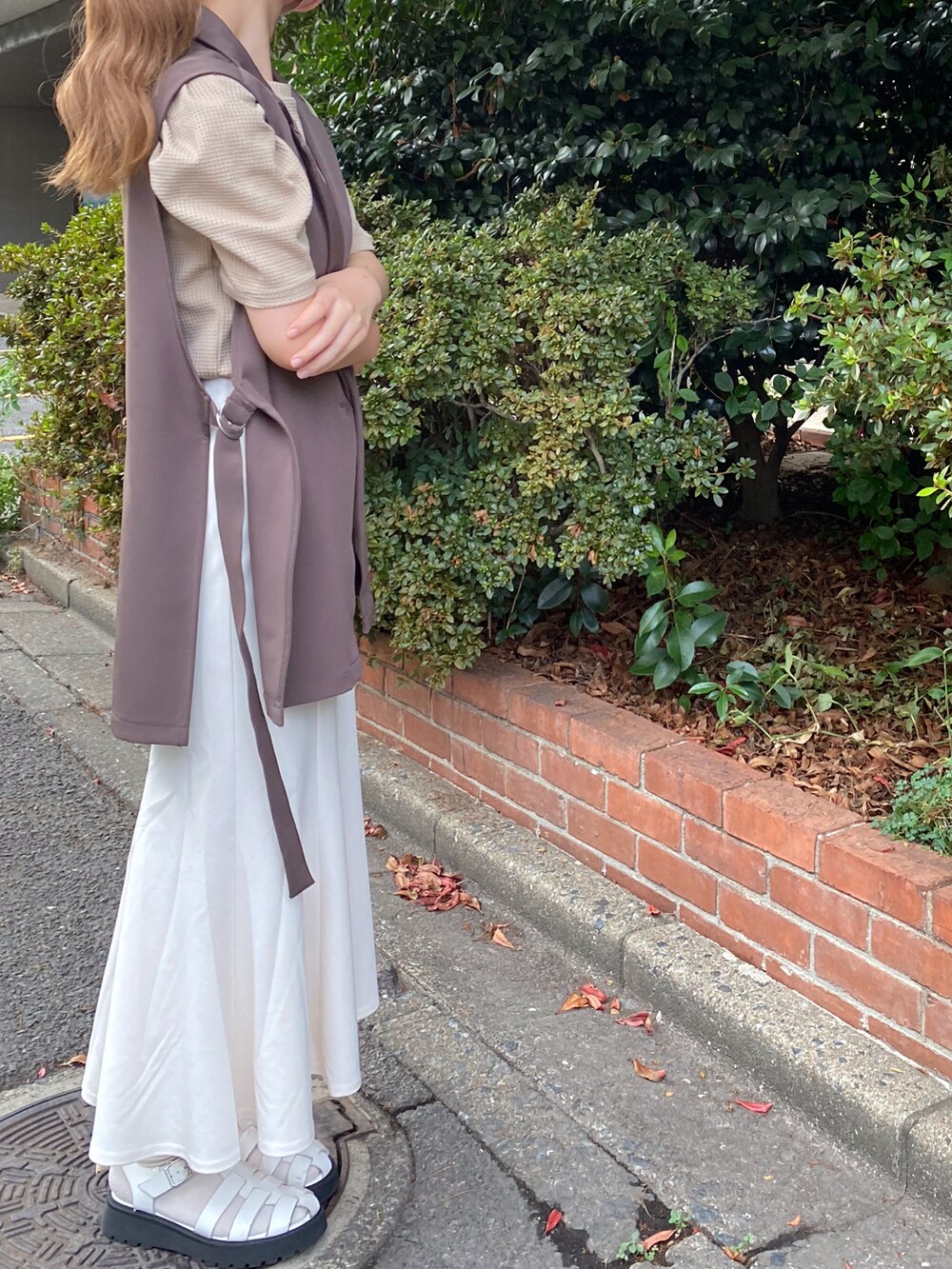 ブラウン系のベスト、ブラウン系のTシャツ/カットソー、ホワイト系のスカートを着用したレディースの夏コーディネートの2枚目の写真