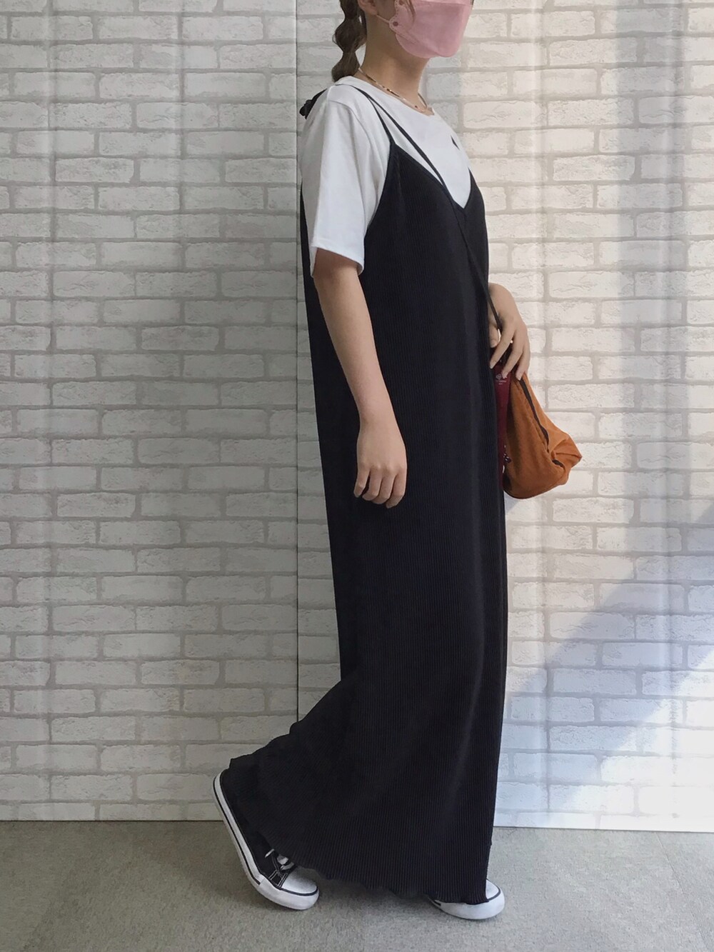 ブラック系のジャンパースカート、ブラック系のスニーカー、ホワイト系のTシャツ/カットソーを着用したレディースの秋コーディネートの2枚目の写真