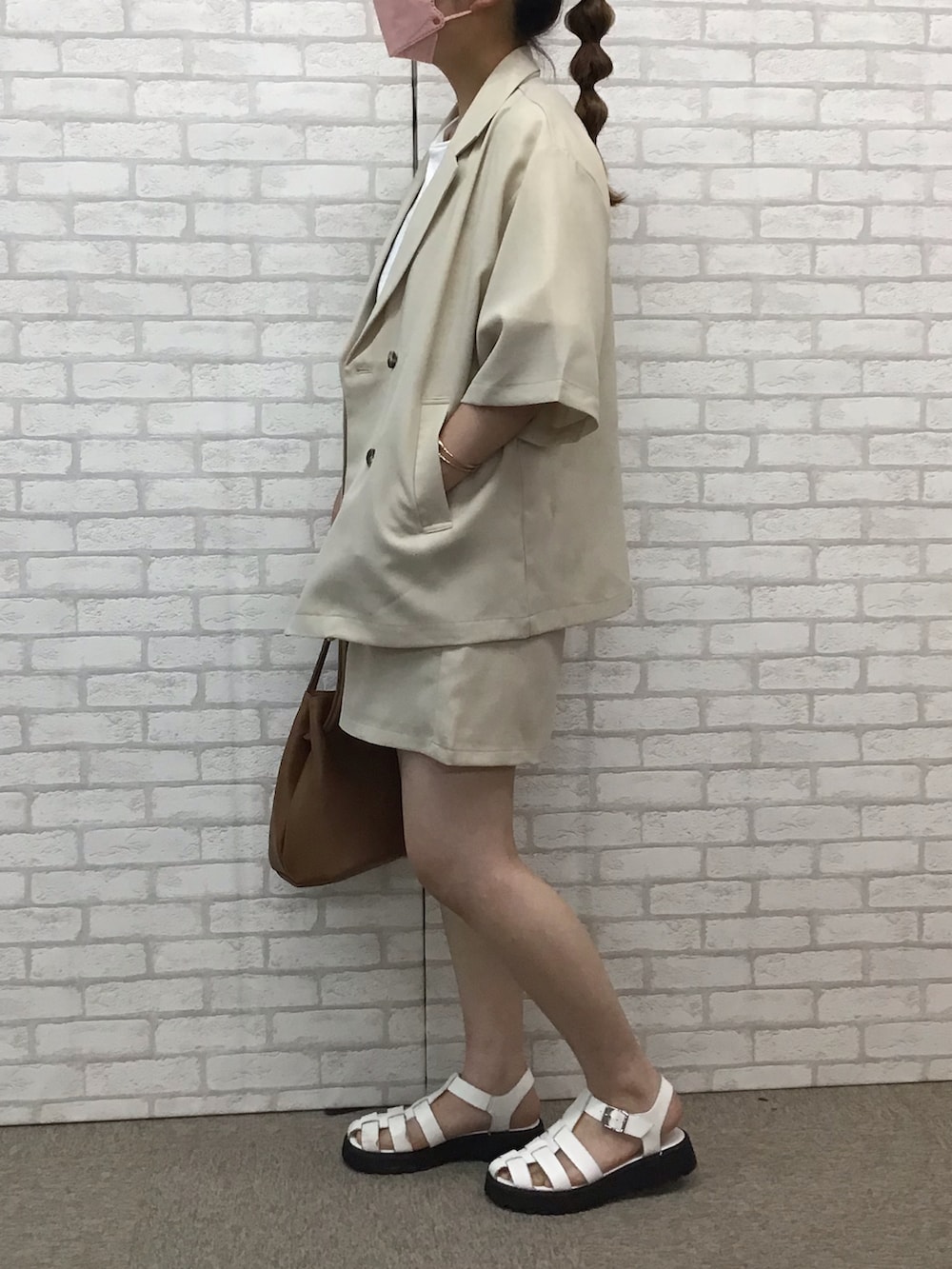 ベージュ系のセットアップ、ホワイト系のTシャツ/カットソー、ホワイト系のサンダルを着用したレディースの夏コーディネートの2枚目の写真
