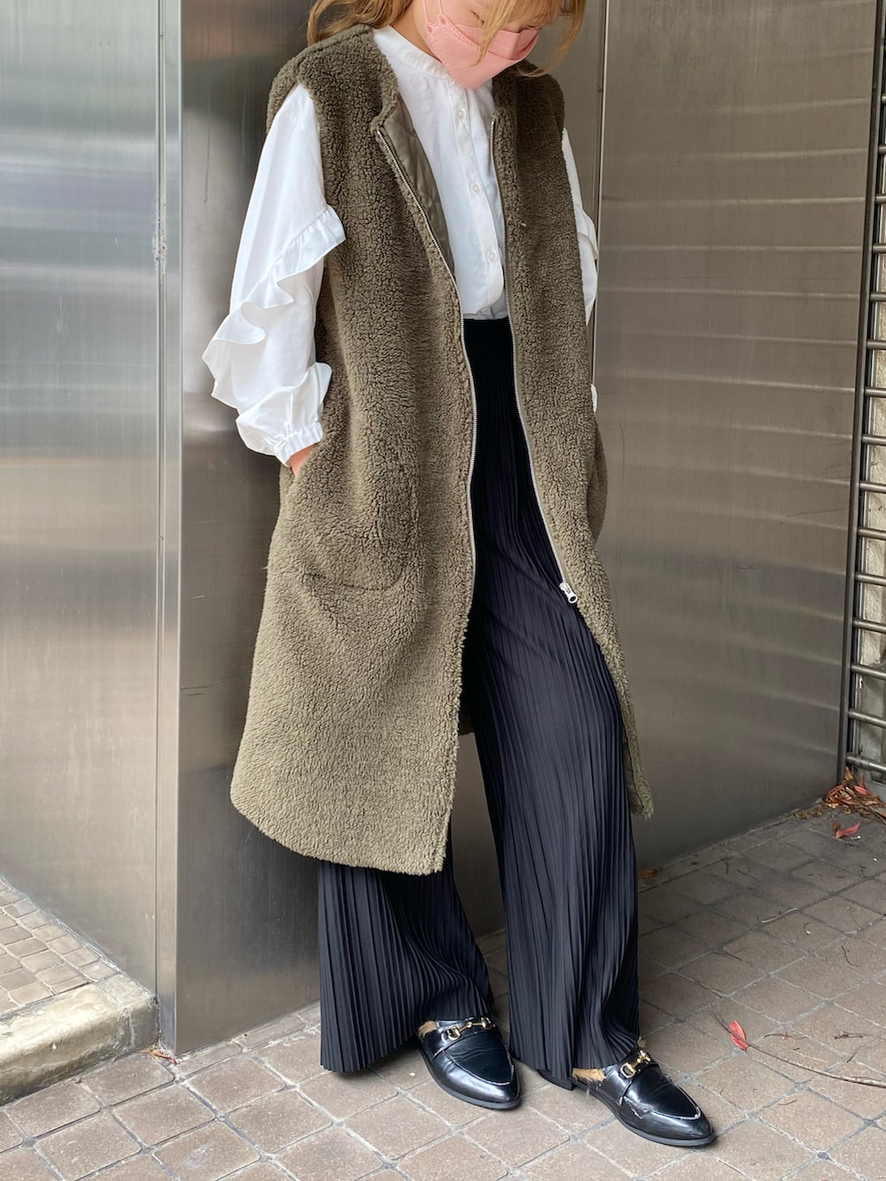 グリーン系のベスト、ホワイト系のシャツ/ブラウス、ブラック系のパンツを着用したレディースの秋コーディネートの2枚目の写真