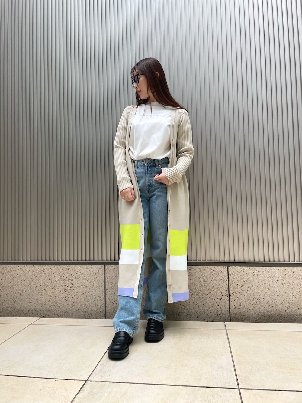 ベージュ系のワンピース、ブルー系のデニムパンツを着用したレディースの冬コーディネートの2枚目の写真