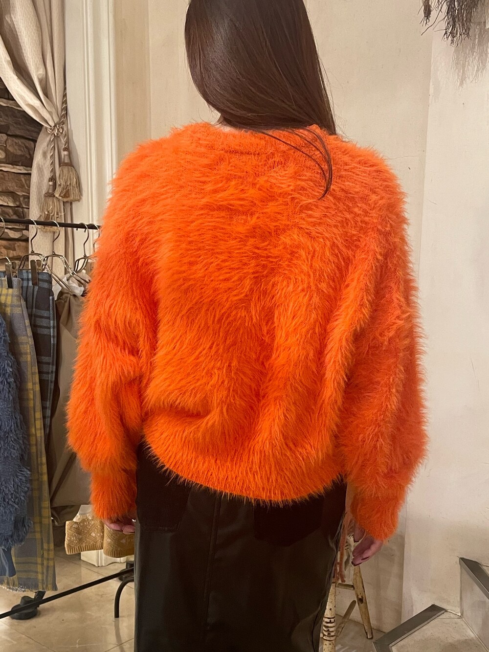 オレンジ系のニット/セーター、ブラック系のスカートを着用したレディースの秋コーディネートの4枚目の写真