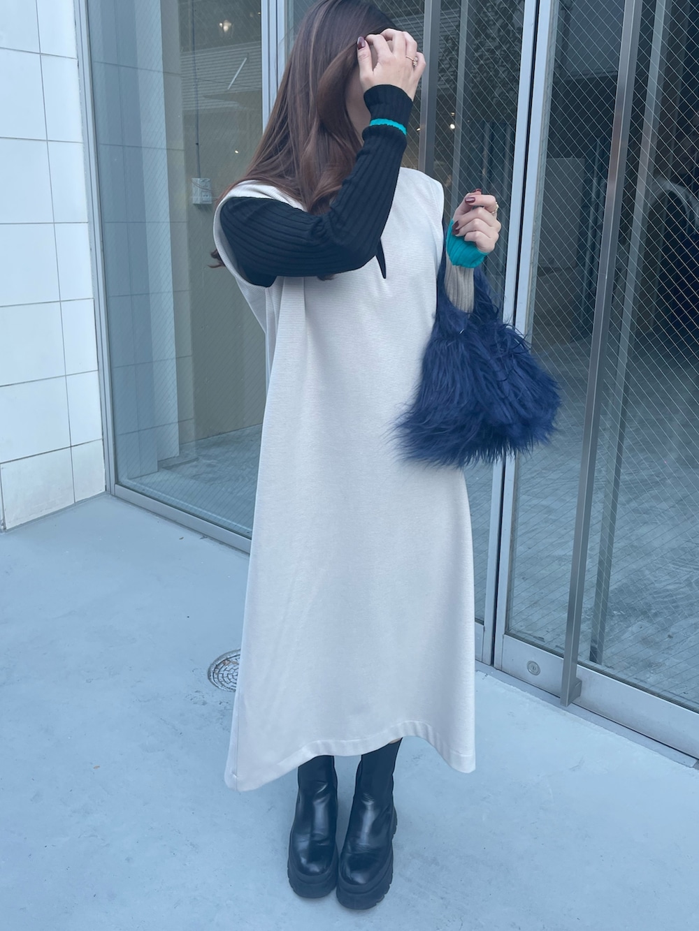 ブルー系のハンドバッグ、ブラック系のニット/セーター、ホワイト系のワンピースを着用したレディースの秋コーディネートの2枚目の写真