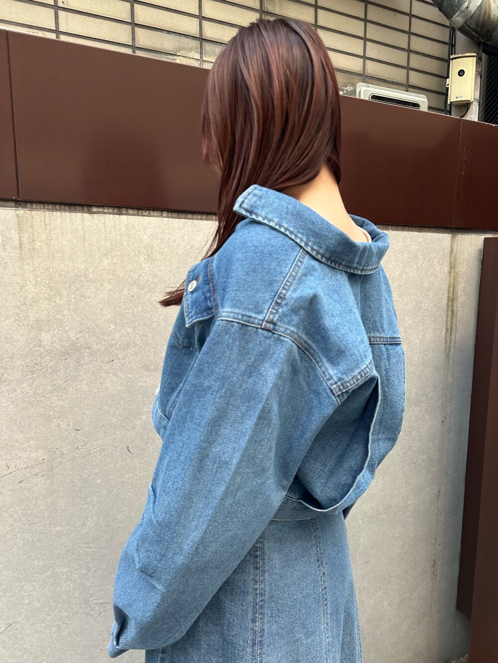 ブルー系のデニムジャケット、ブルー系のスカート、ホワイト系のスニーカーを着用したレディースの春コーディネートの2枚目の写真