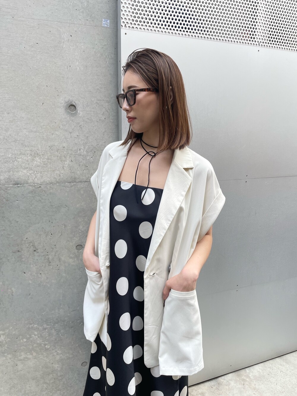 ブラック系のスカート、ブラウン系のサングラスを着用したレディースの春コーディネートの2枚目の写真