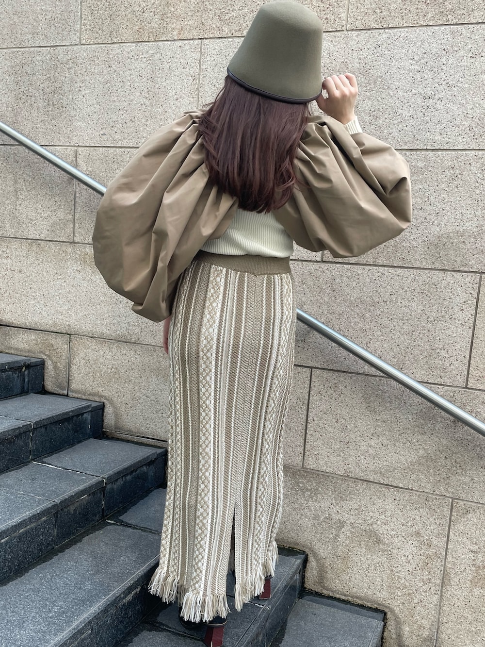 ベージュ系のスカート、ブラウン系のカーディガン/ボレロ、グリーン系のハットを着用したレディースの秋コーディネートの3枚目の写真