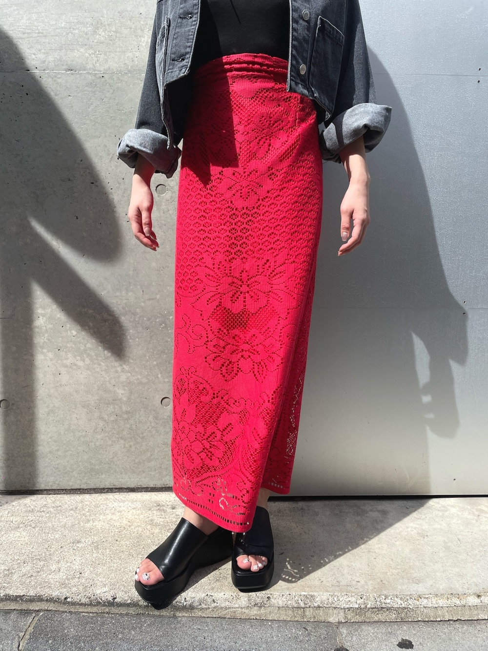 ブラック系のサンダル、レッド系のスカート、ブラック系のデニムジャケットを着用したレディースの春コーディネートの4枚目の写真