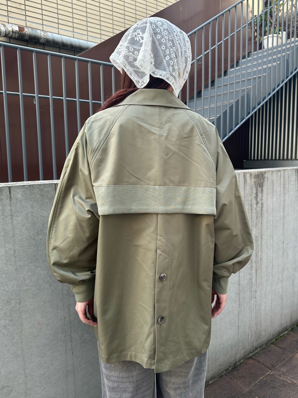 グリーン系のトレンチコートを着用したレディースの春コーディネートの3枚目の写真