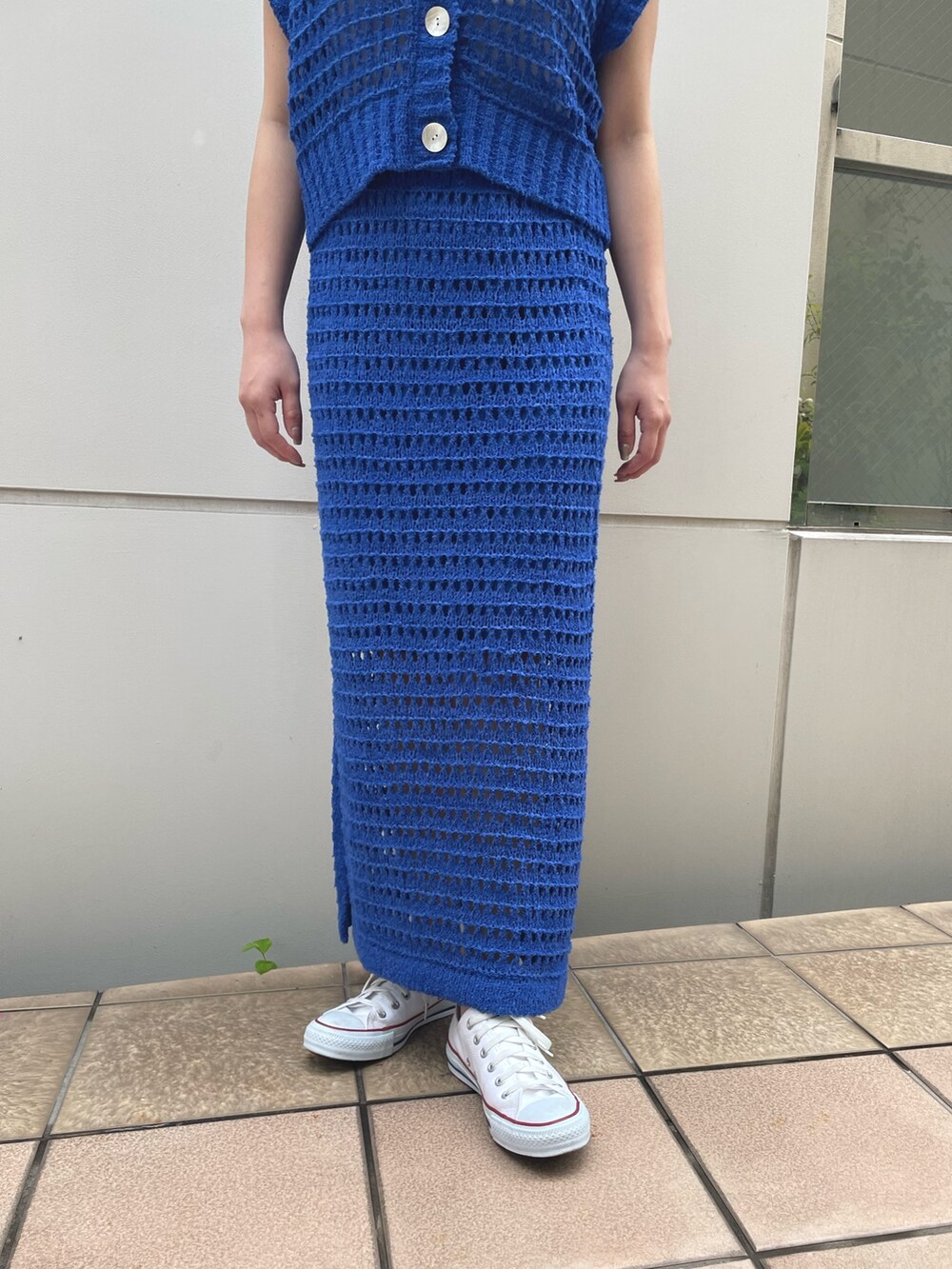 ブルー系のスカート、ブルー系のベスト、ホワイト系のスニーカーを着用したレディースの春コーディネートの5枚目の写真