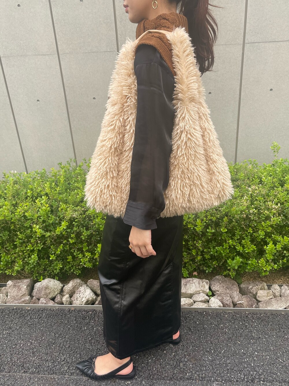 イエロー系のベスト、ベージュ系のトートバッグ、ブラック系のスカートを着用したレディースの秋コーディネートの5枚目の写真