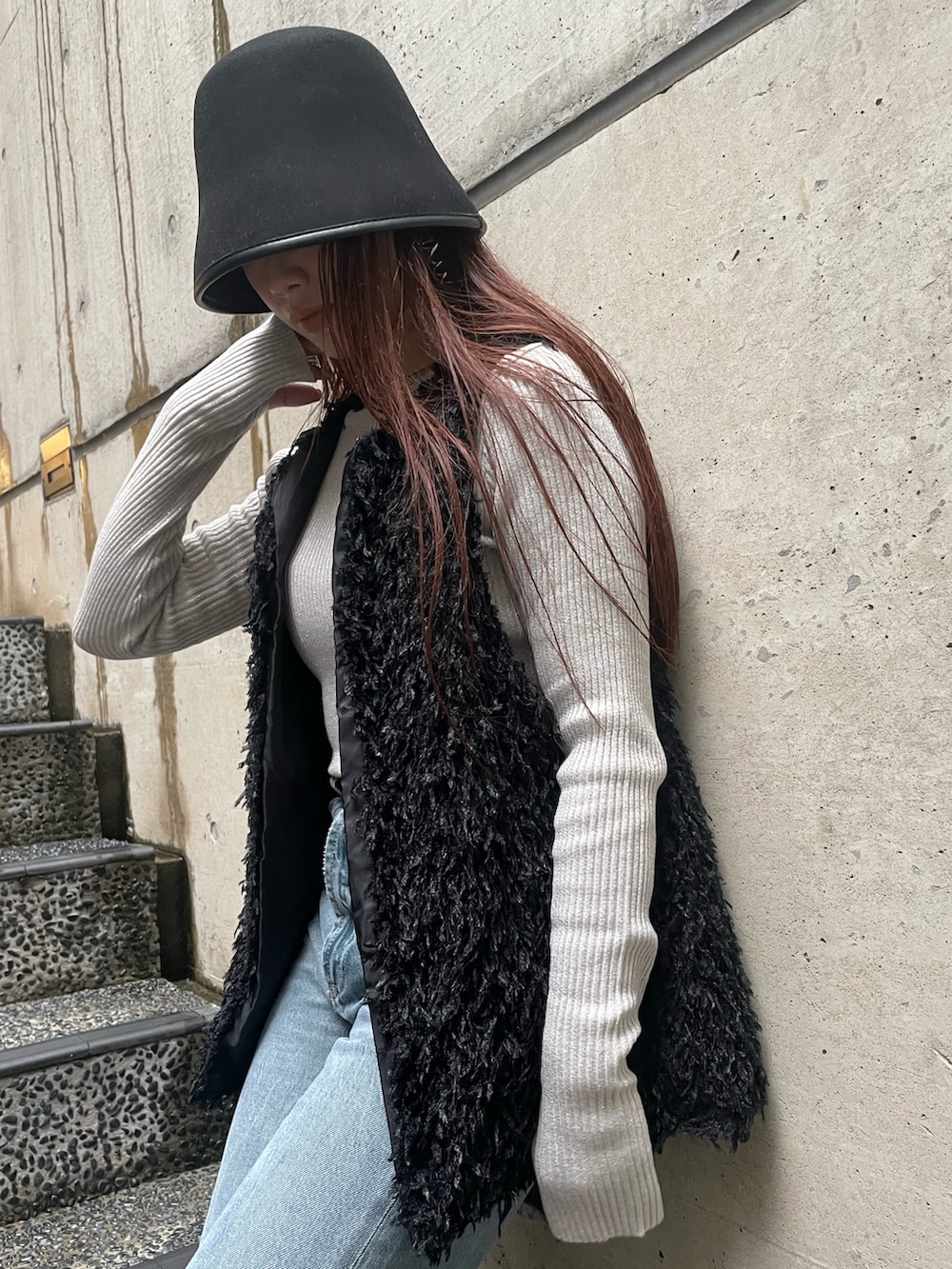 ブラック系のベスト、ホワイト系のニット/セーター、ブラック系のハットを着用したレディースの冬コーディネートの5枚目の写真