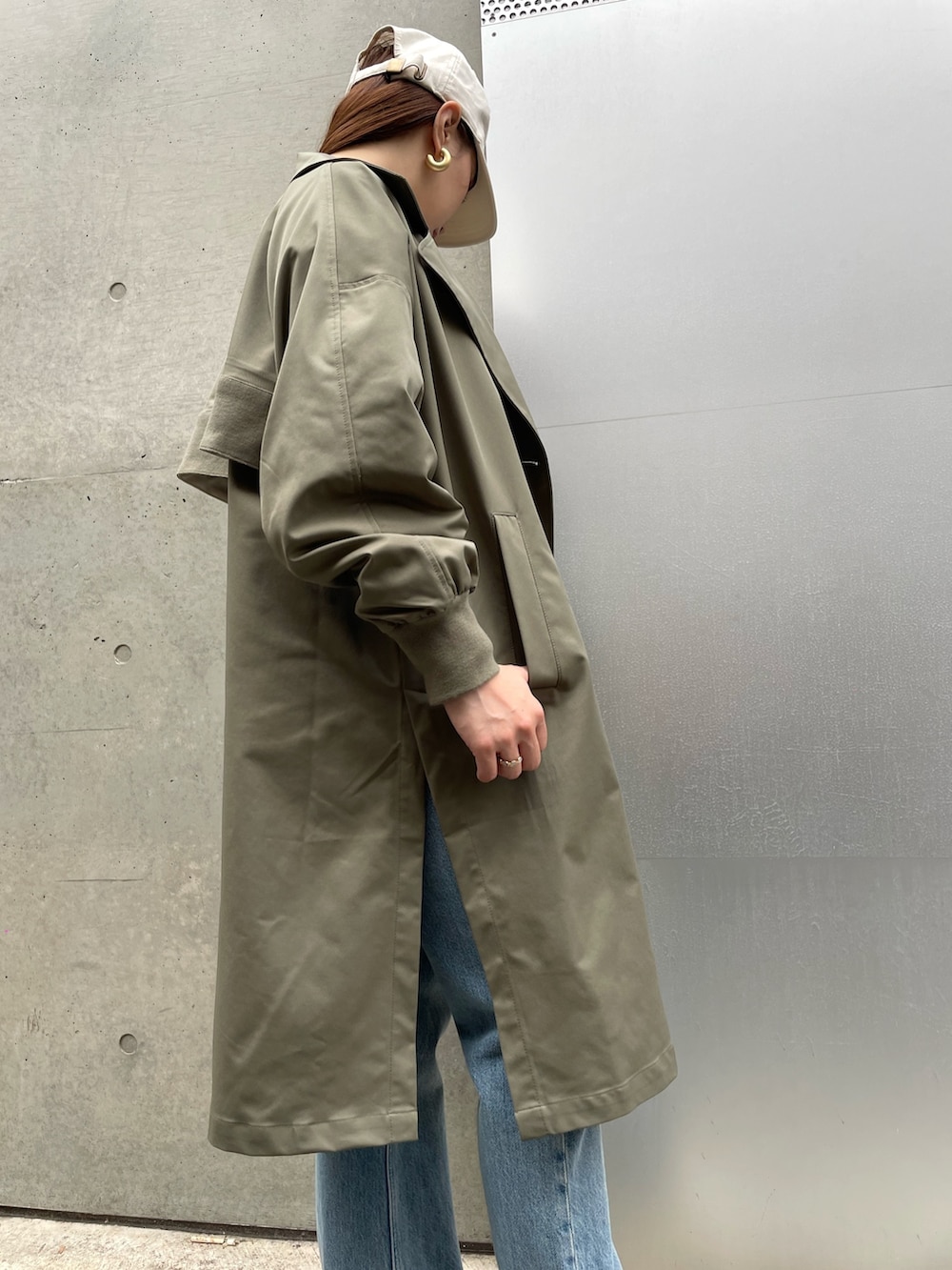 グレー系のスウェット、グリーン系のトレンチコート、ブルー系のデニムパンツを着用したレディースの春コーディネートの3枚目の写真