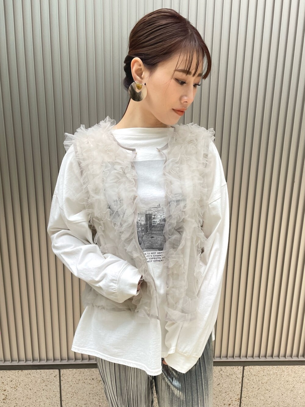 グレー系のベスト、ブラック系のその他パンツ、イエロー系のピアス（両耳用）を着用したレディースの冬コーディネートの2枚目の写真